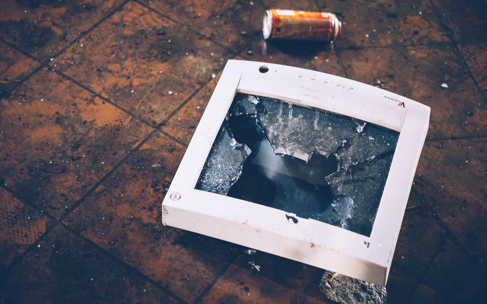 A broken old monitor lying on a tiled floor