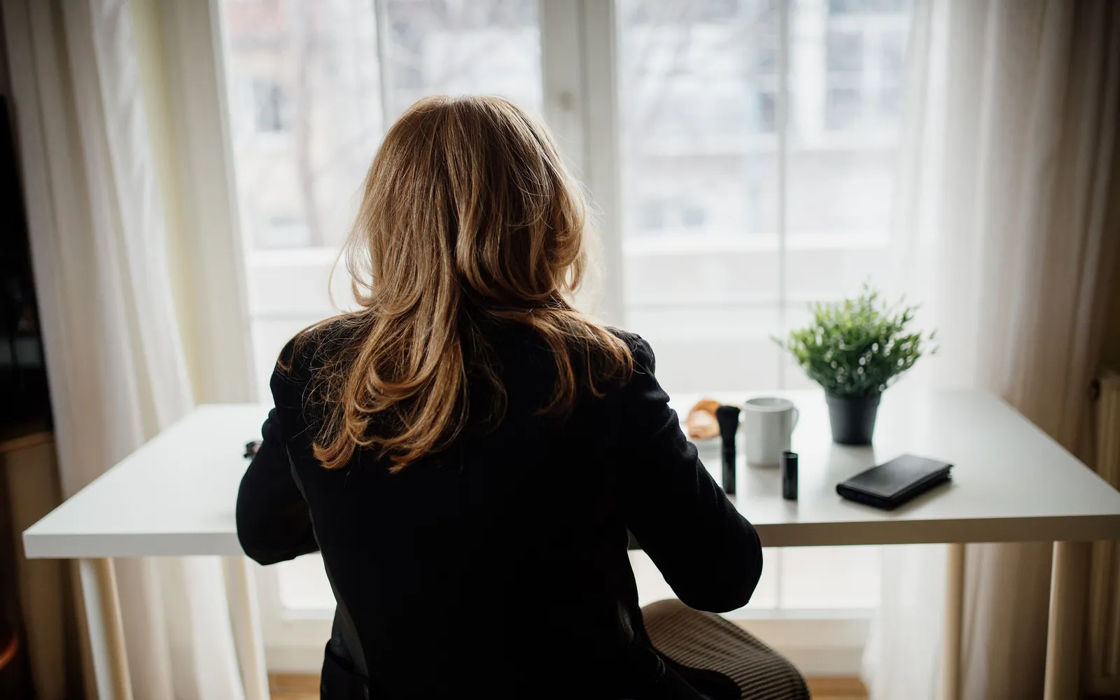 A person working at a white desk by a bright window