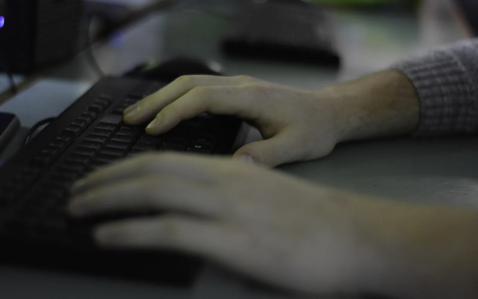 Hands resting on a backlit keyboard in a dark room