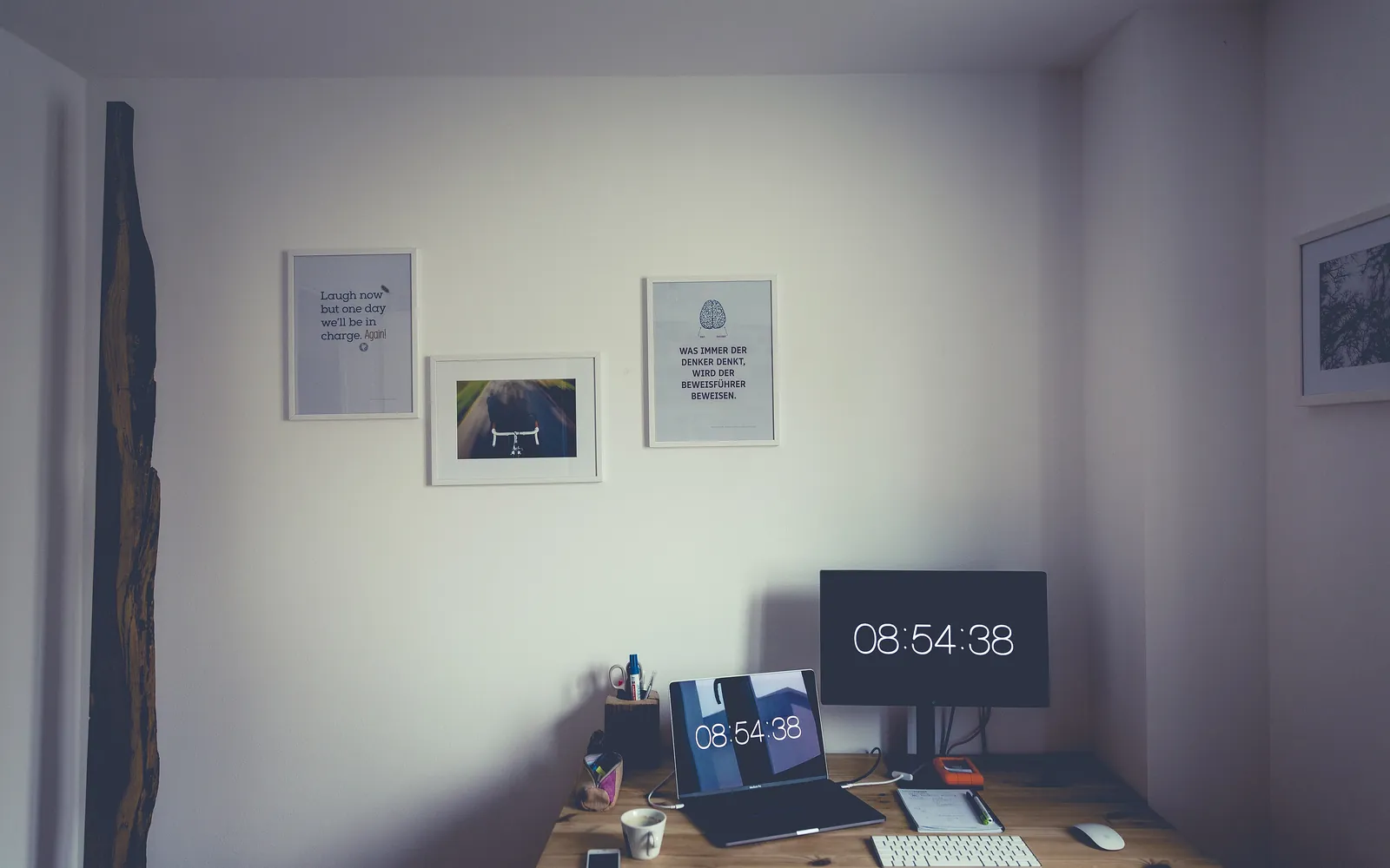 Un escritorio minimalista con un monitor y un teclado junto a una pared blanca
