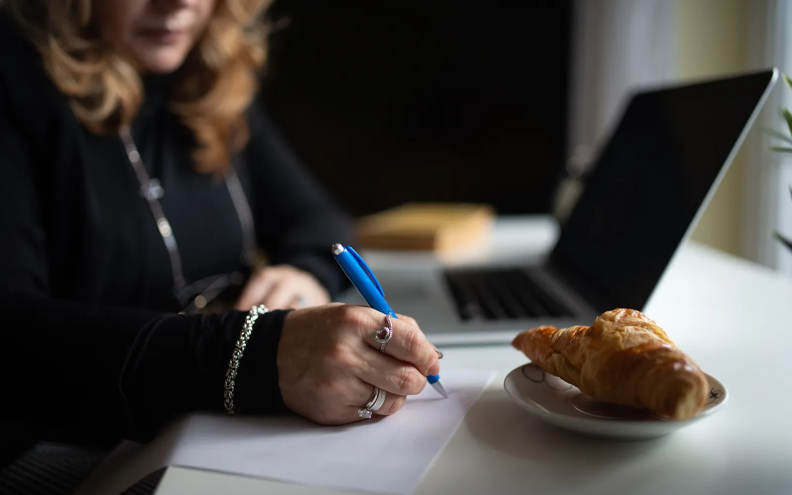 Una persona tomando notas en papel junto a un portátil