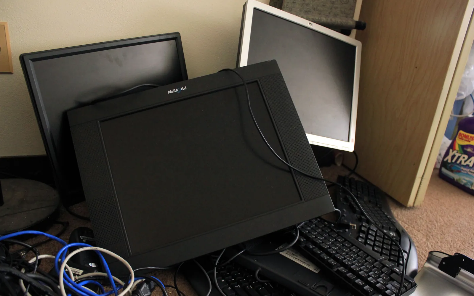 Old monitors, a keyboard and network cables piled on a desk