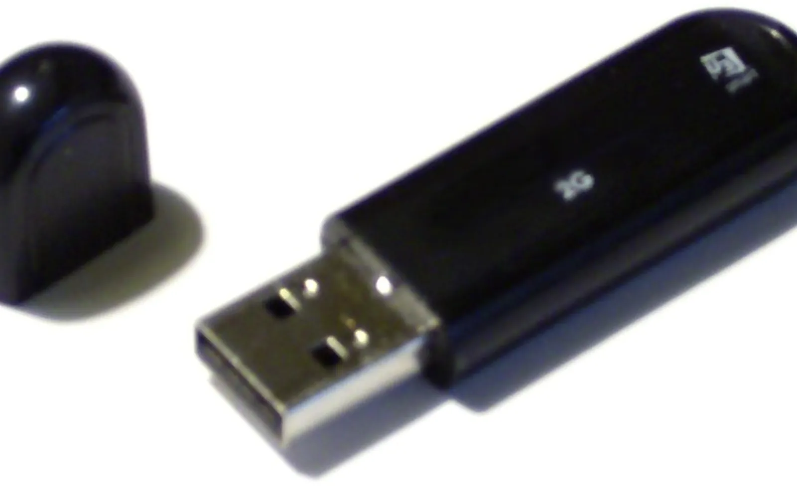 An unbranded black USB flash drive lying next to its cap